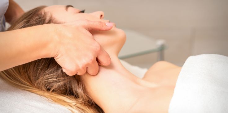 a therapist performing a lymphatic drainage massage on a woman's neck.