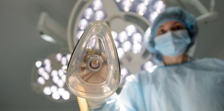 Doctor holding an anesthesia mask in a hospital operating room.