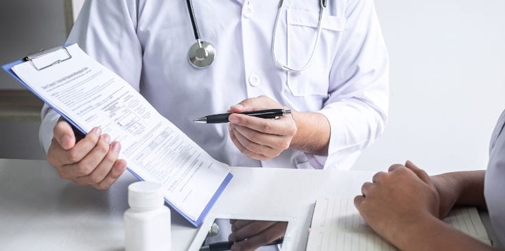 a doctor reviewing a medical form with a patient at a desk.