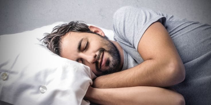 a man peacefully sleeping on a white pillow.