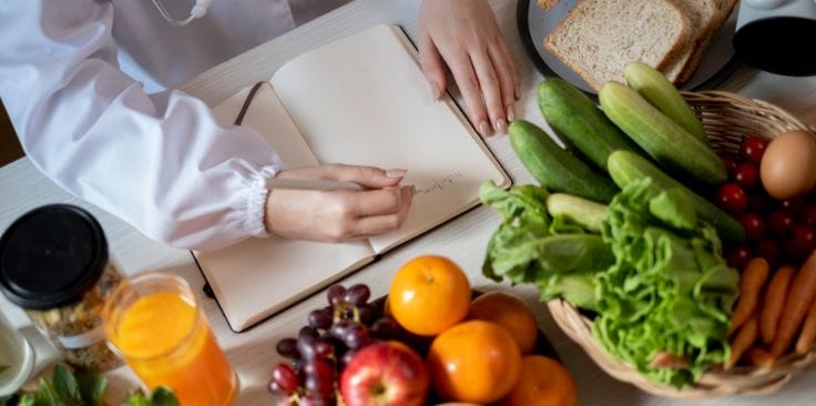 a person planning a balanced diet with fresh fruits and vegetables for nutritional support.