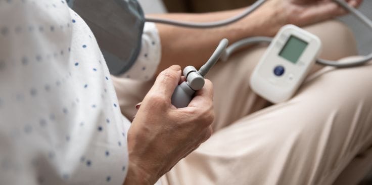 Close-up of a person using a digital blood pressure monitor at home.