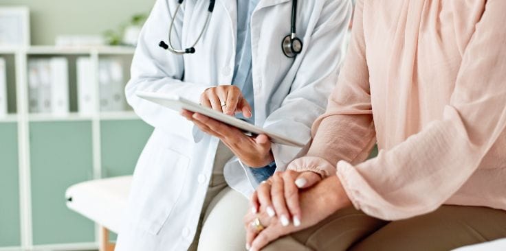 Doctor showing liver biopsy results on a tablet to a patient.