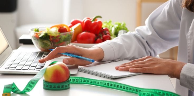 Nutritionist planning a healthy diet with fresh fruits, vegetables, and measuring tape on the table.