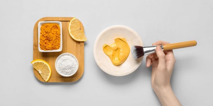 Turmeric paste being prepared with lemon slices and clay, illustrating the creative use of turmeric in skincare routines.