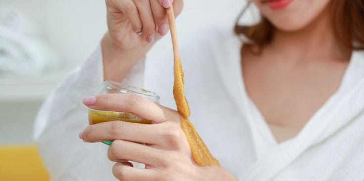 A woman applying turmeric paste to her hand, showcasing how turmeric supports skin care and natural remedies.