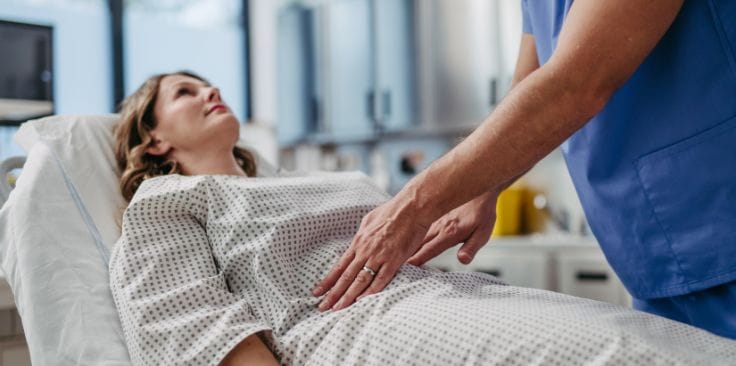 a doctor gently examining the abdomen of a woman lying on a hospital bed, possibly related to a medical condition like endometriosis.