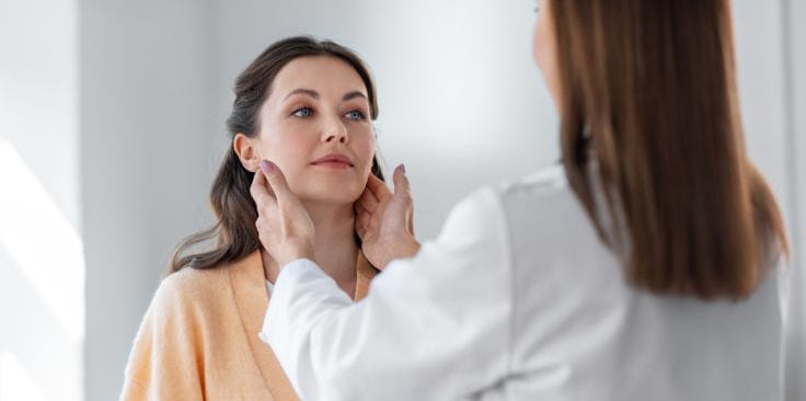 doctor examining a woman's neck for swollen lymph nodes. 