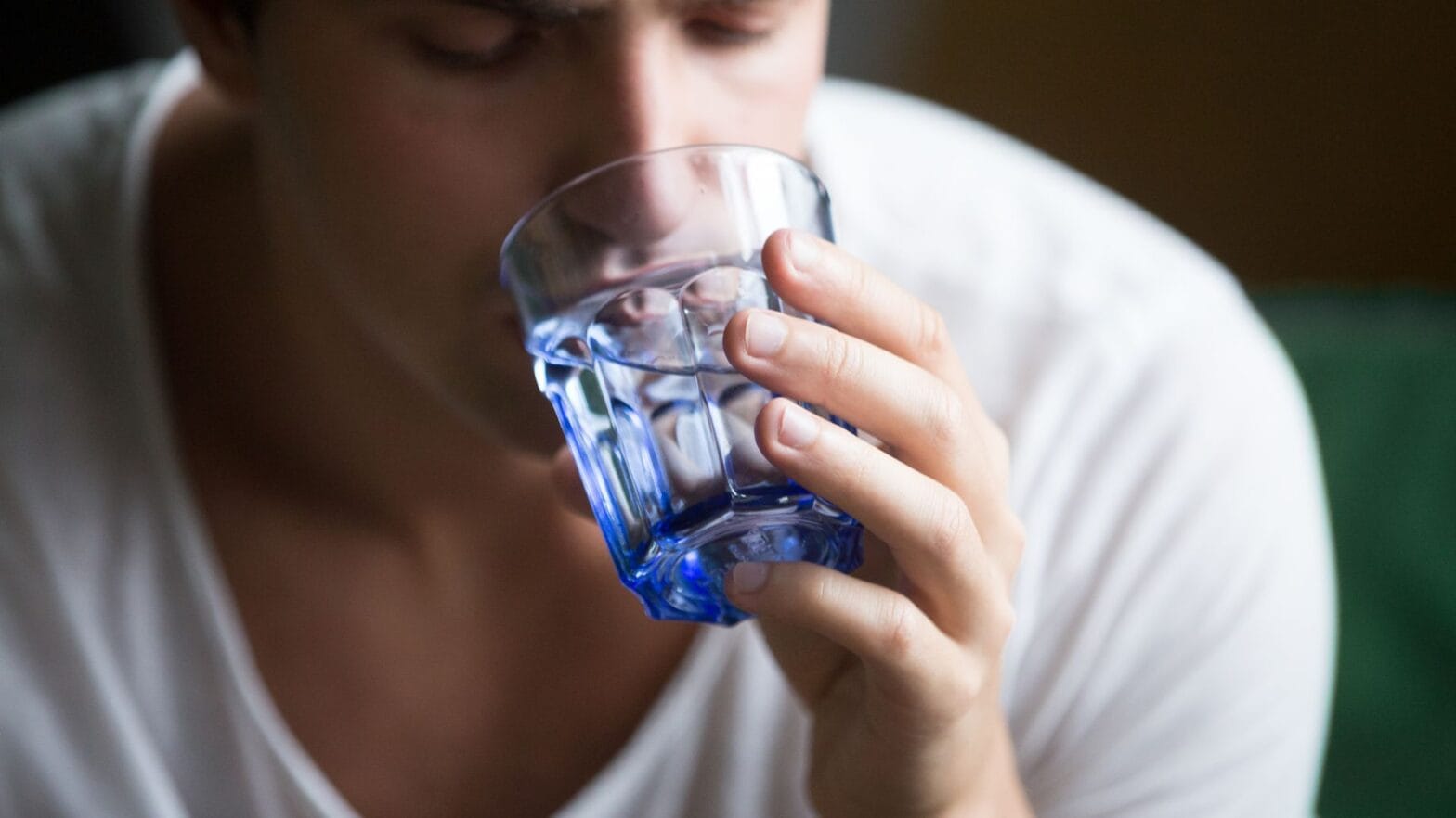 Man drinking water from a blue glass